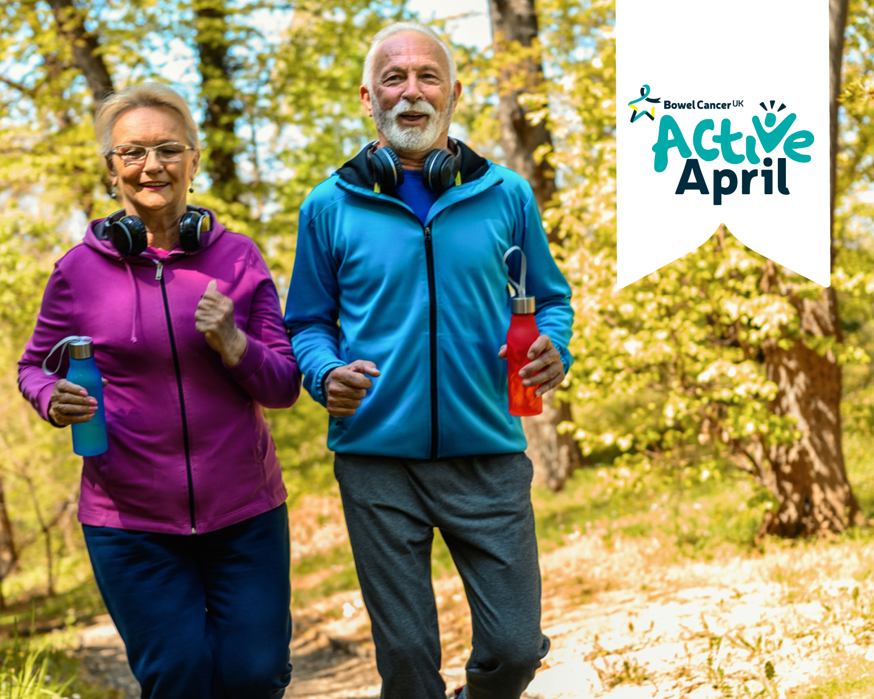 A photo of two people jogging. They are facing the camera. The person on the left of the image is wearing a bright pink jacket and dark blue jogging bottoms. They have a pair of head phones around their neck. In their right hand they are holding a light blue water bottle. The person on the right is wearing a light blue jacket and grey jogging bottoms. They also have a pair of head phones around their neck. In their left hand they are holding a red water bottle. In the background are some trees. In the top right hand corner is a white illustrated banner. On this banner is the ActiveApril logo in light and dark teal.
